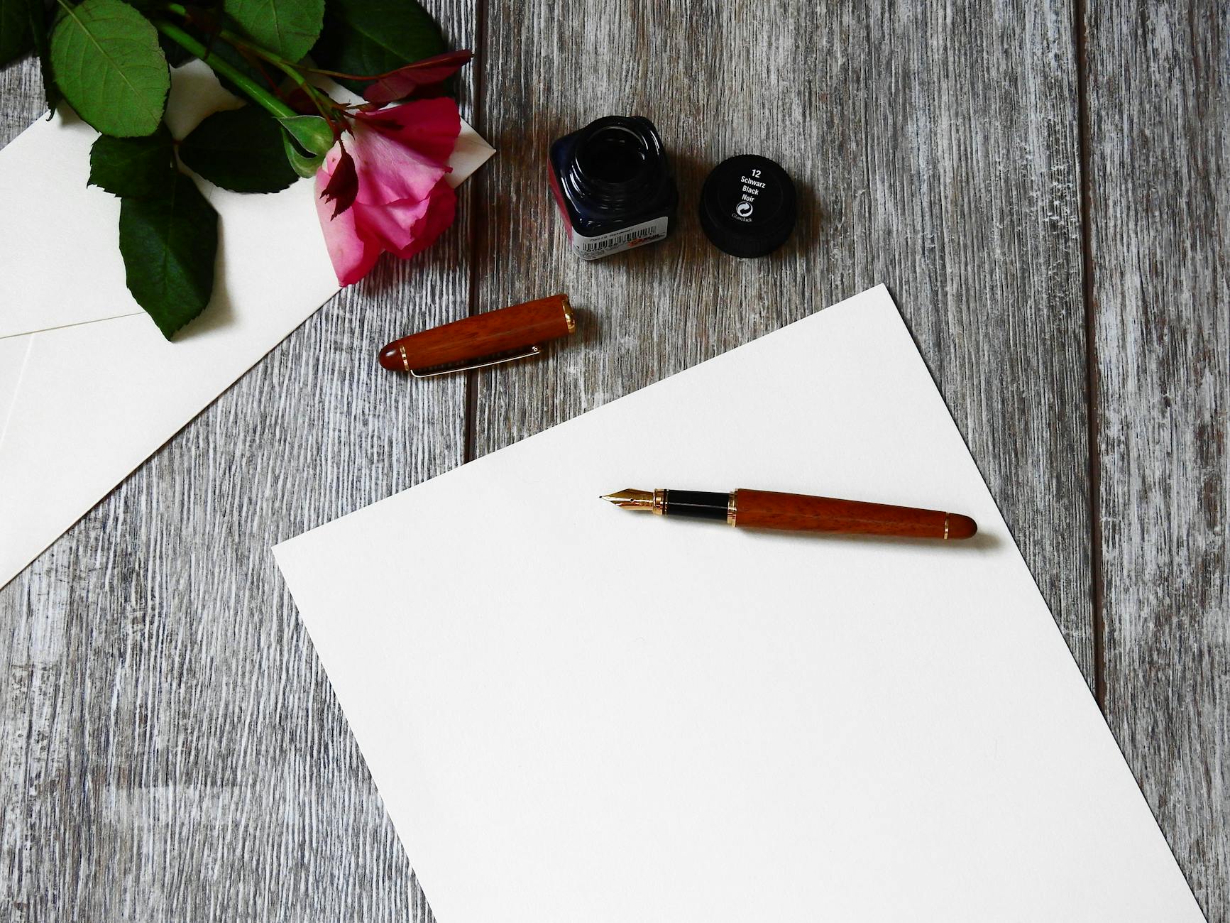 A piece of stationary with a pen and a rose